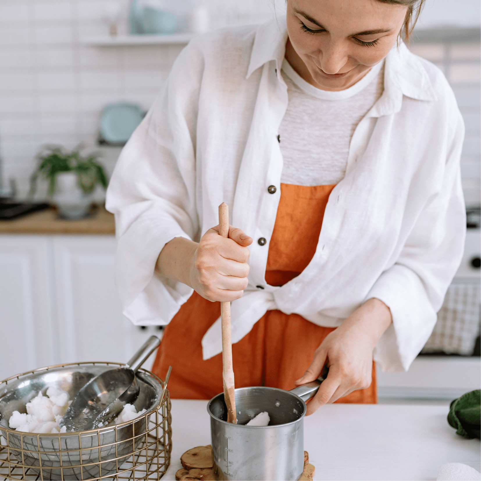 woman mixing melted wax in pot with wooden spoon